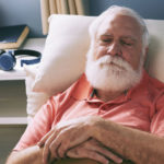 An older man taking a nap on the couch.